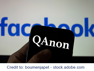 QAnon organization logo seen on the smartphone which is placed on Facebook logos. Credit: boumenjapet - stock.adobe.com