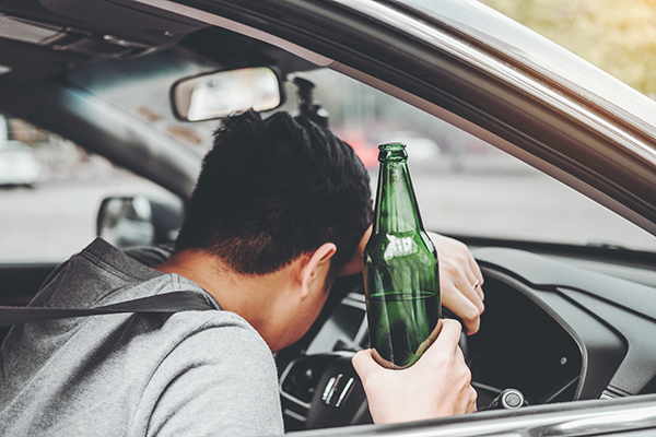 image of man driving with beer bottle in hand