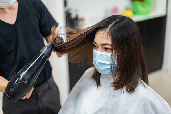 image of woman getting hair services while wearing a mask